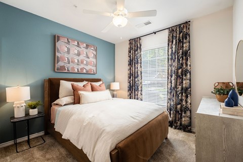 A bedroom with a large bed and a ceiling fan.