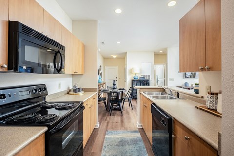 A kitchen with a black stove top oven and wooden cabinets.