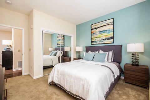 A bedroom with a large bed and a painting on the wall.