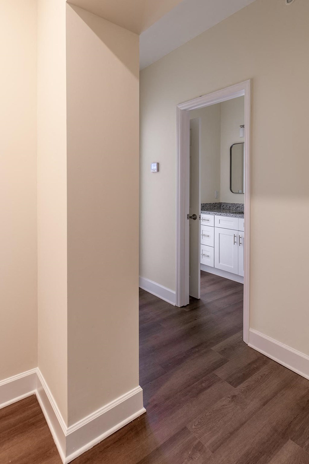 a view of a hallway with a door to a bathroom and a sink