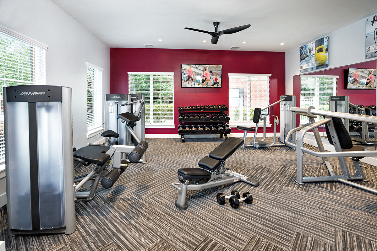 a gym with cardio equipment and a television