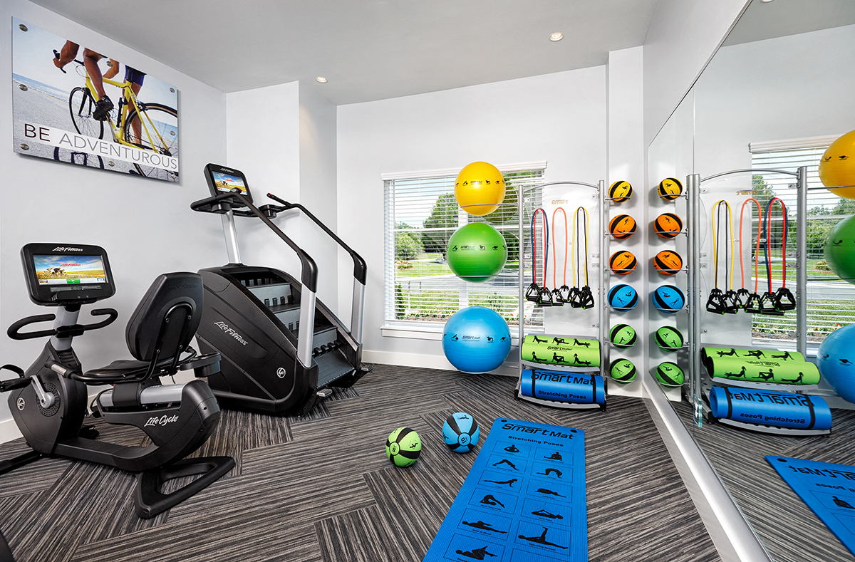 a gym with weights and cardio equipment on the floor and a window