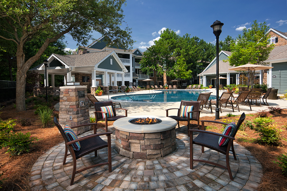 a backyard with a pool and patio with chairs and a fire pit