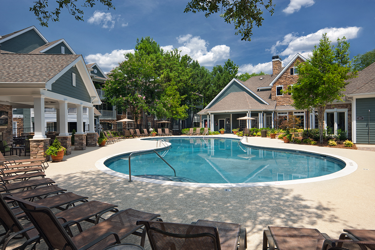 a swimming pool with chairs in front of a house
