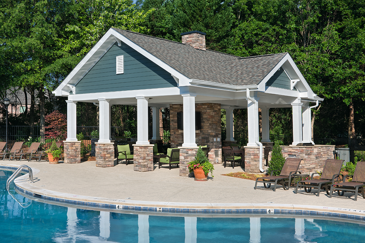a swimming pool with a pool house with columns and a pool