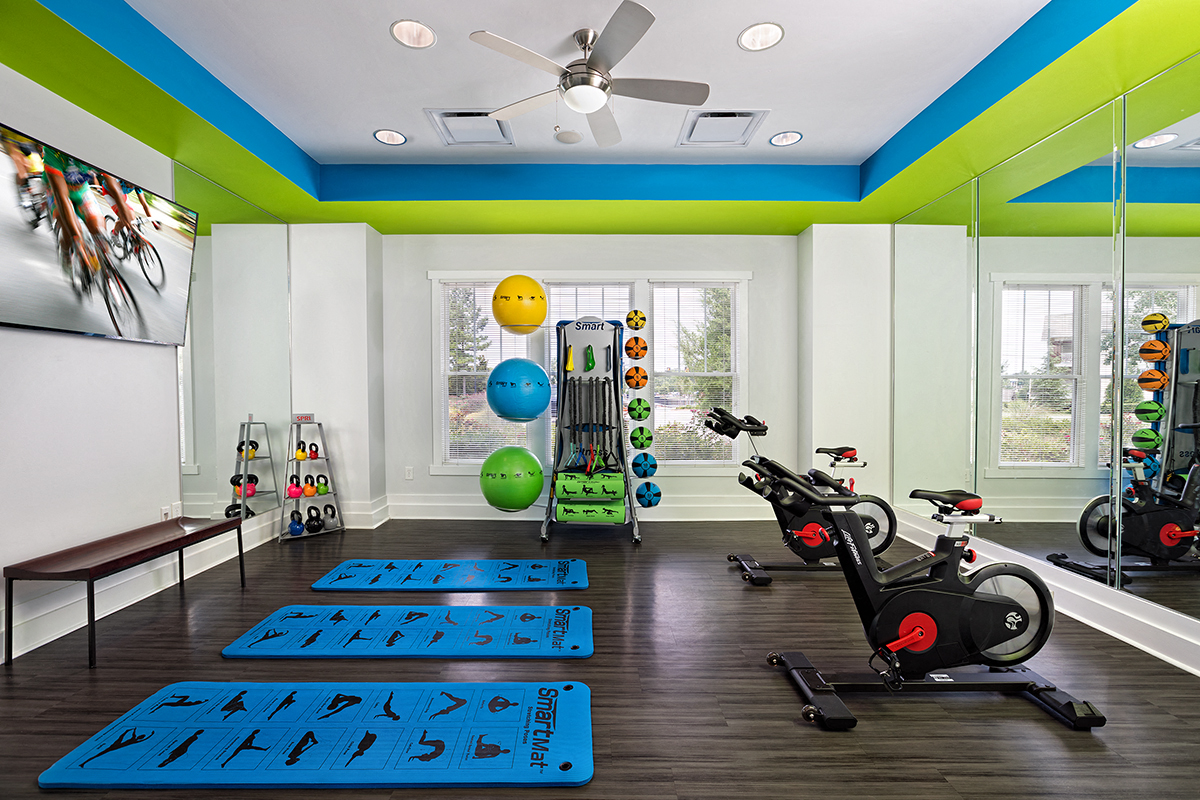 a home gym with exercise equipment and a ceiling fan