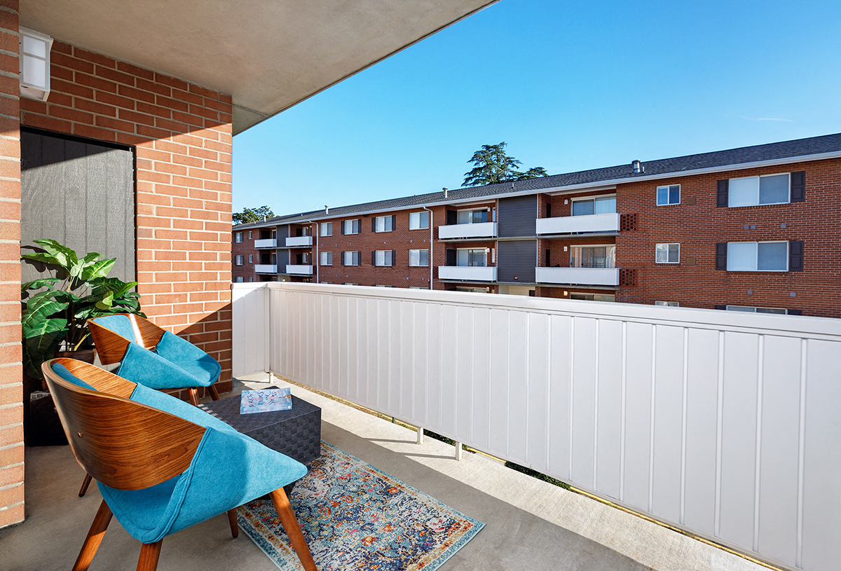 a balcony with two chairs and a table in front of a brick building