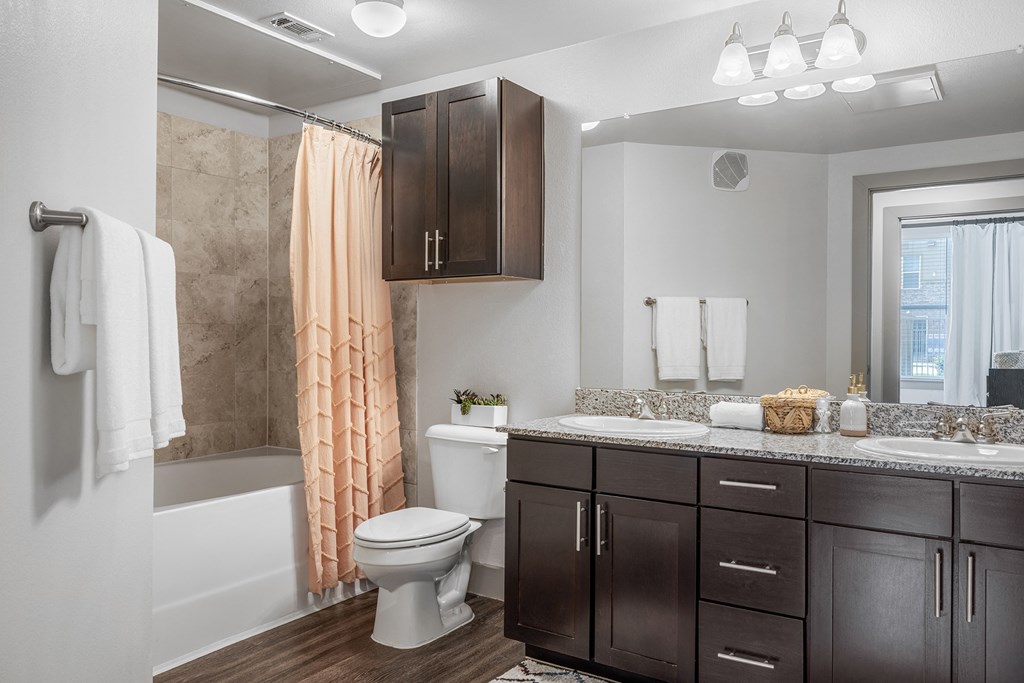bathroom with tiled shower/tub and double vanity sink with granite coutertops