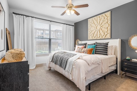 bedroom with queen size bed, large windows and ceiling fan.