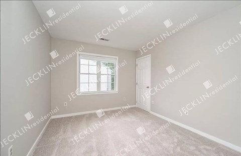 A sparsely furnished room with a window and a door.