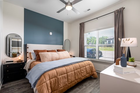 A bedroom with a bed, nightstand, and window.