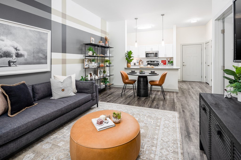 a living room with a couch a table and chairs and a kitchen in the background