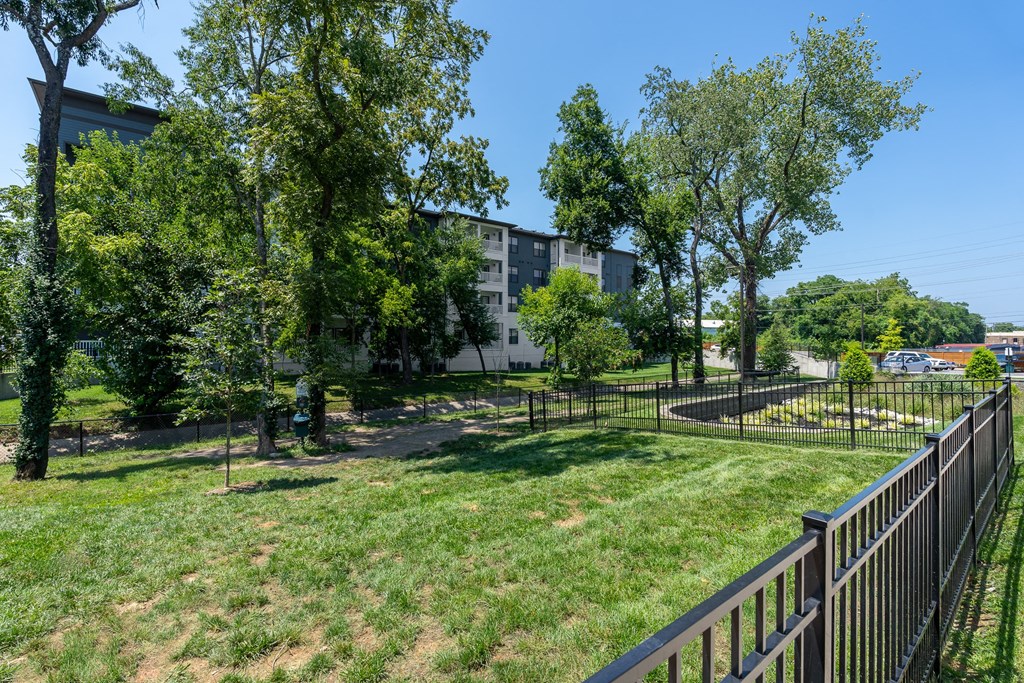a grassy area with trees and a fence in front of a building
