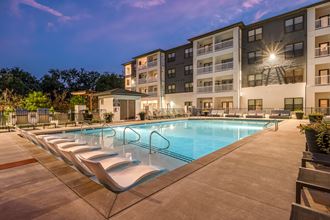 a swimming pool with chaise lounge chairs and a building in the background