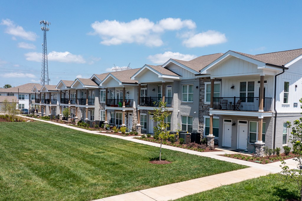 a row of houses on a sidewalk next to a green lawn