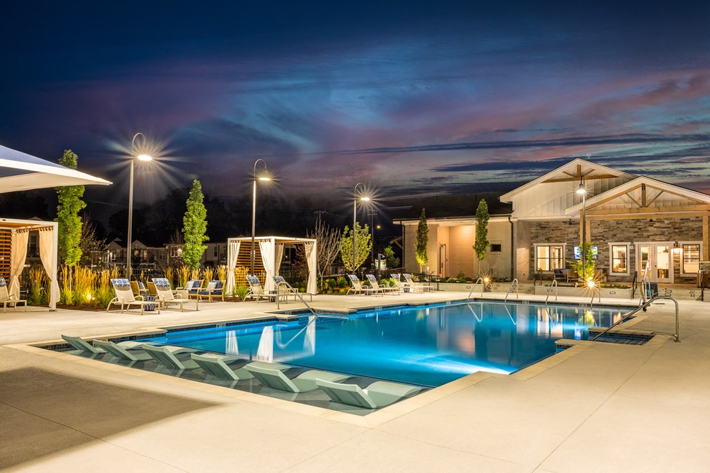 a swimming pool at night with a building in the background