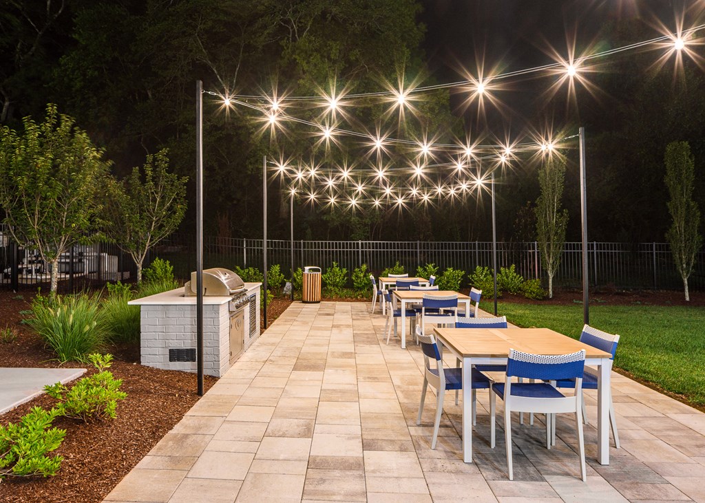 a patio with tables and chairs and lights in the background