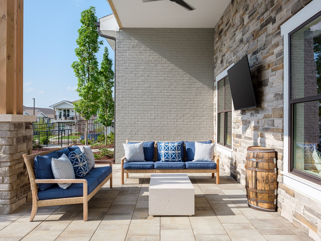 a patio with blue couches and chairs and a television
