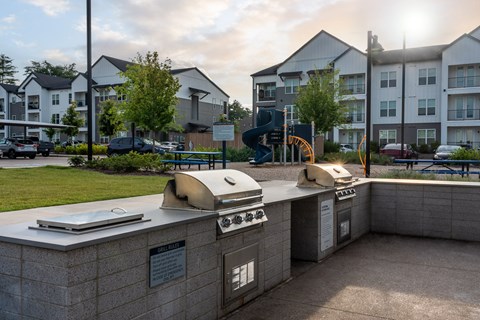 A sunny day at a residential complex with a bbq grill in the foreground.
