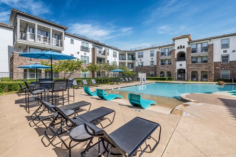 A sunny day at the poolside with chairs and umbrellas.