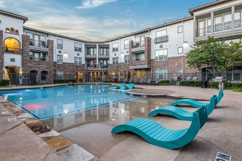 A swimming pool with a blue bench in front of a building.