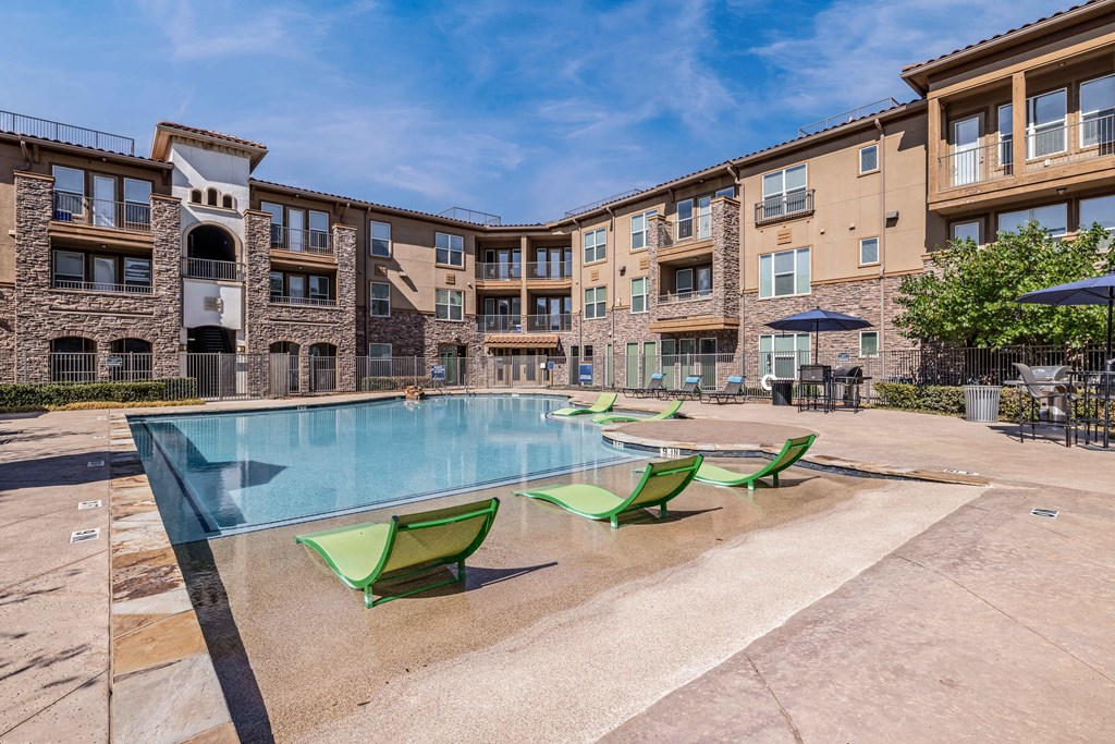 our apartments have a large swimming pool with green chairs