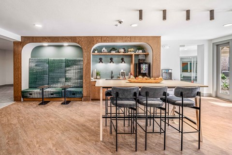 a bar with stools and a counter with chairs in a room with a kitchen