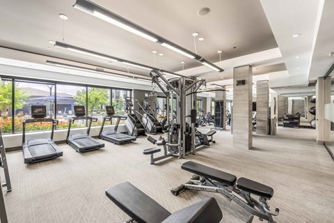 A spacious gym with a variety of equipment and a view of the outdoors.