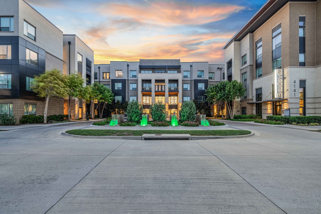 an empty street in front of an apartment building at sunset