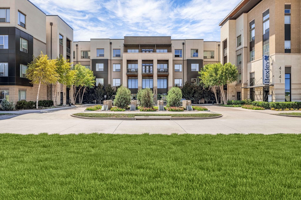 an exterior view of an apartment building with grass and trees