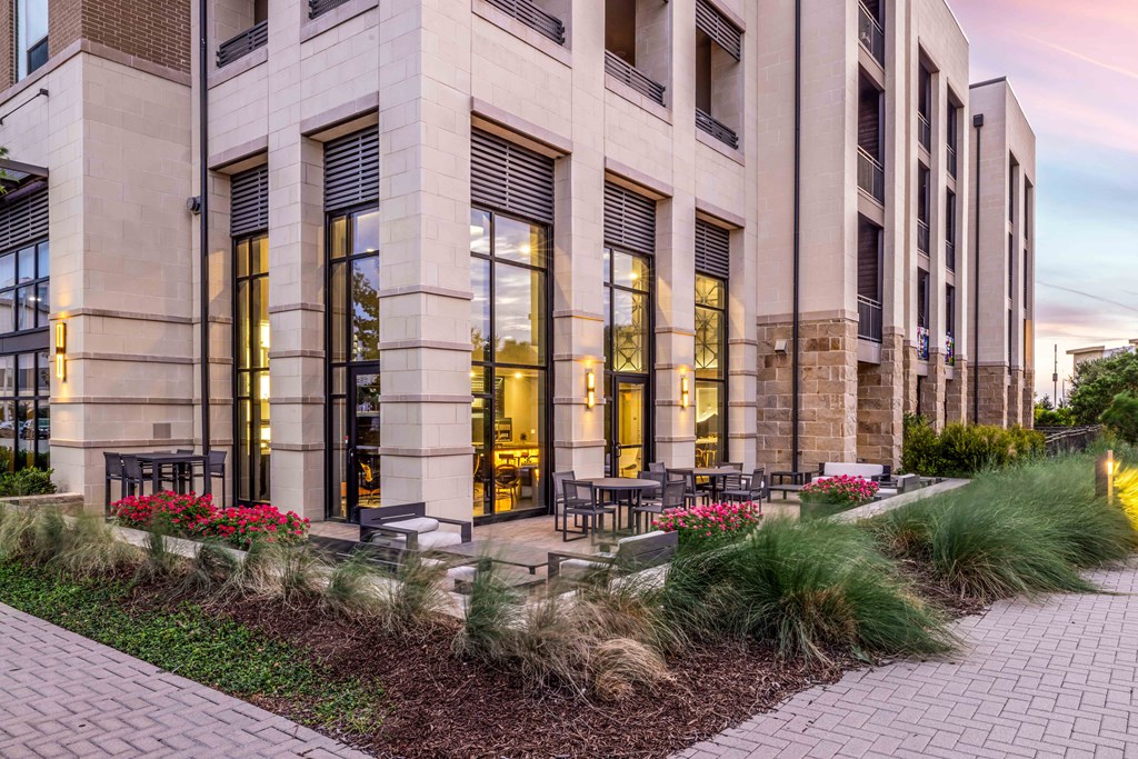 a building with large windows and a patio with tables and chairs