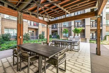 a patio with wooden tables and chairs and an apartment building in the background
