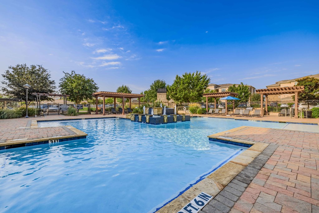 a swimming pool with trees and a blue sky above it