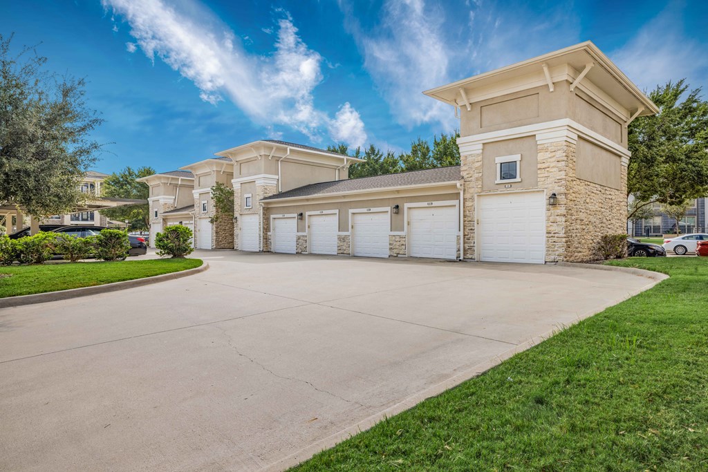 a driveway leading to a building with white garage doors