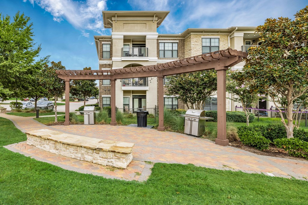 a patio with a stone bench in front of an apartment building