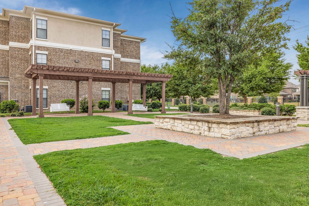 a brick patio with a stone fire pit in front of a building