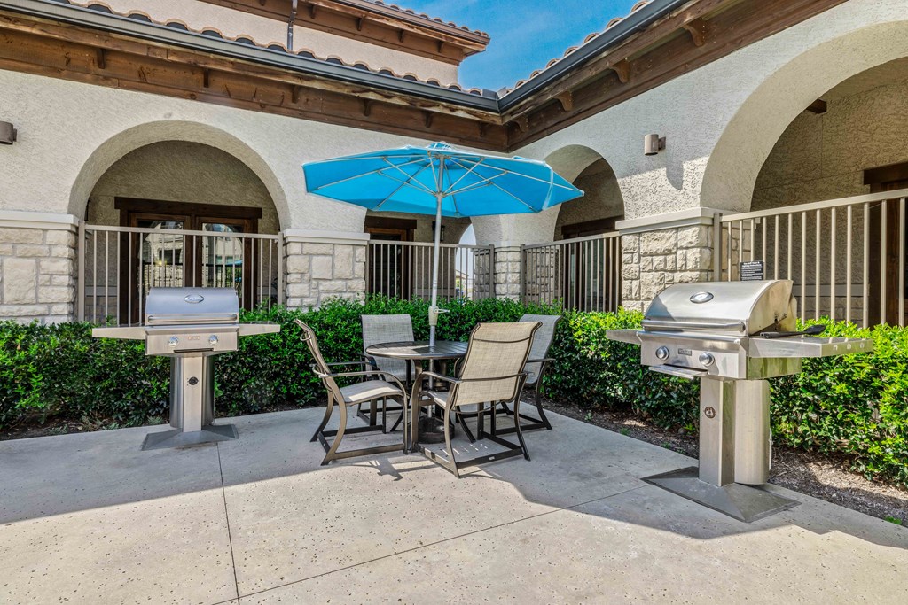 a patio with two bbq grills and a table and chairs