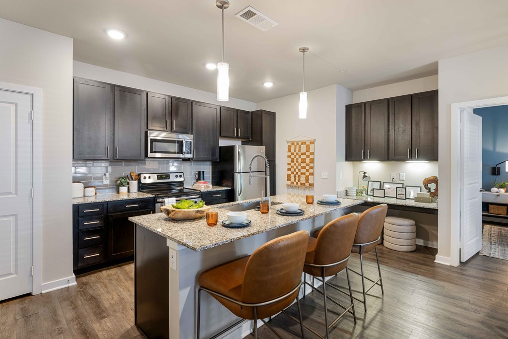 a kitchen with a large island with chairs and a counter top