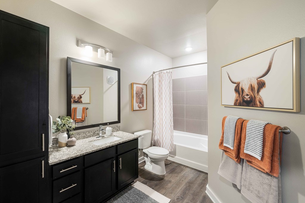 a bathroom with a shower and a toilet and a painting of a bull