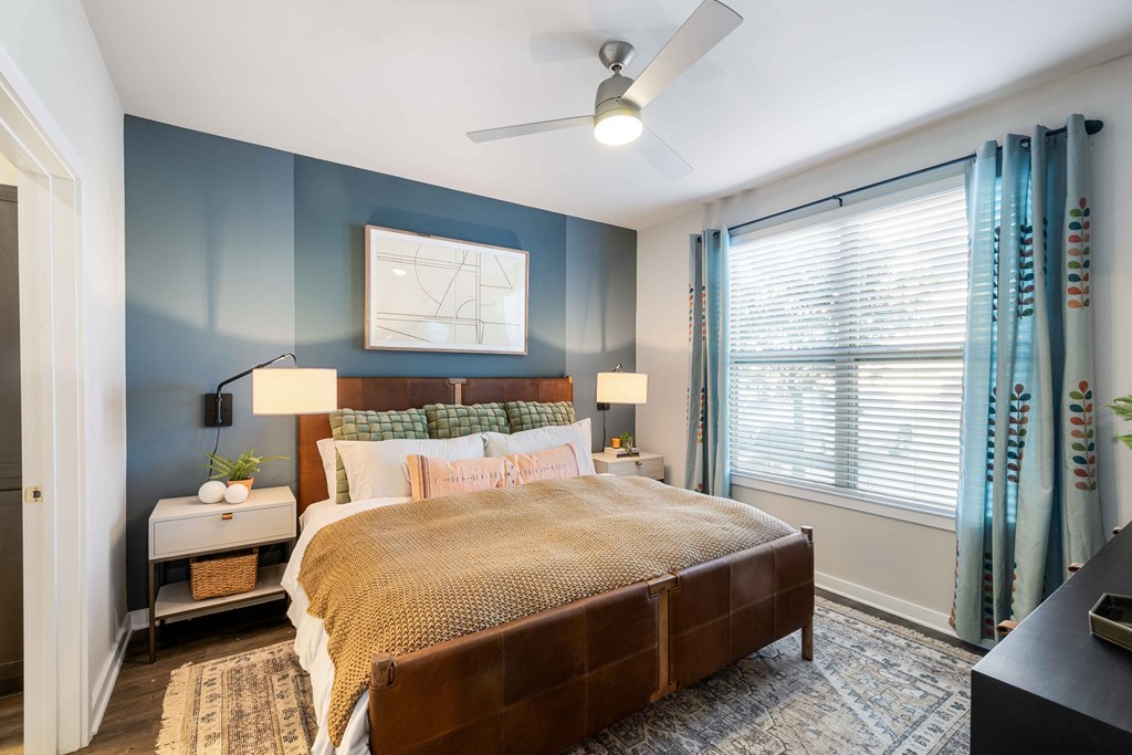 a bedroom with blue walls and a large window and a bed