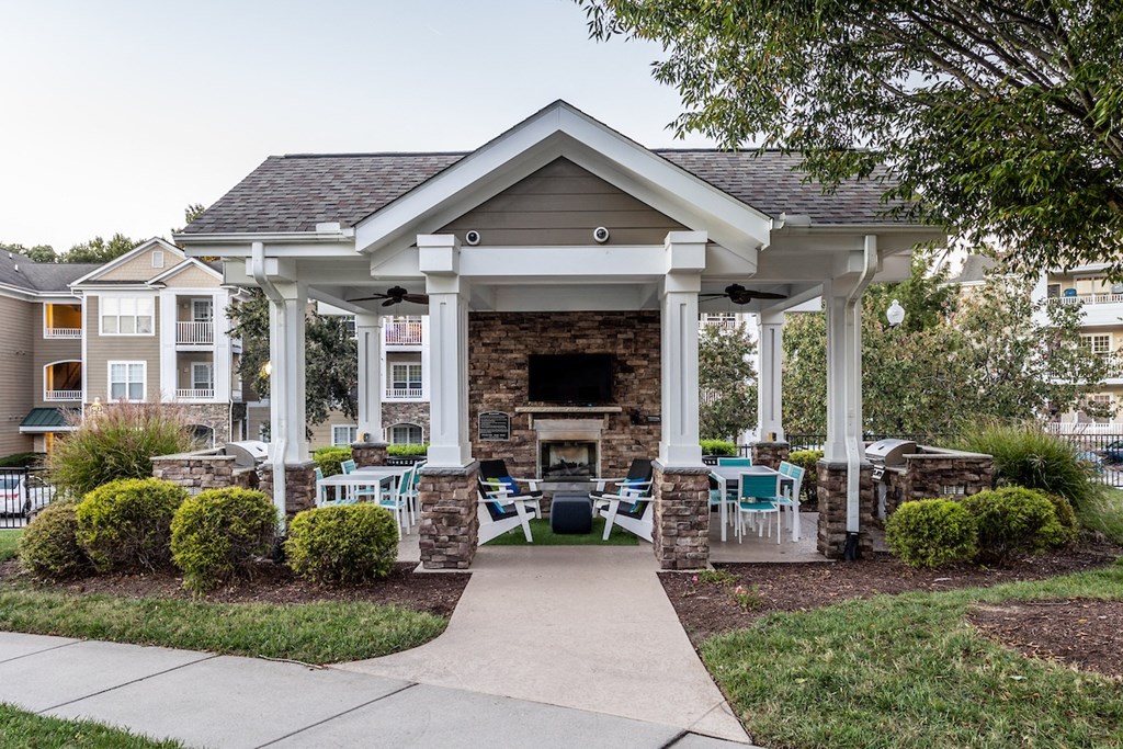 a covered patio with tables and chairs in front of a brick fireplace