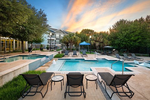 A pool area with chairs and a building in the background.