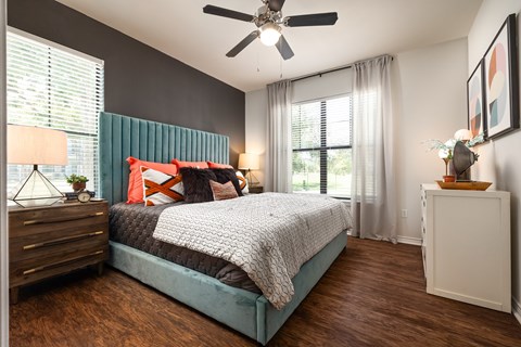 A bedroom with a bed, nightstand, and a ceiling fan.