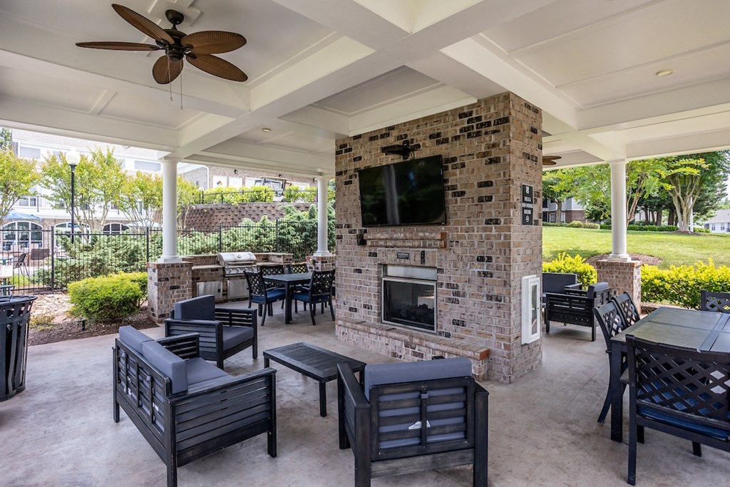 a covered patio with a fireplace and tables and chairs
