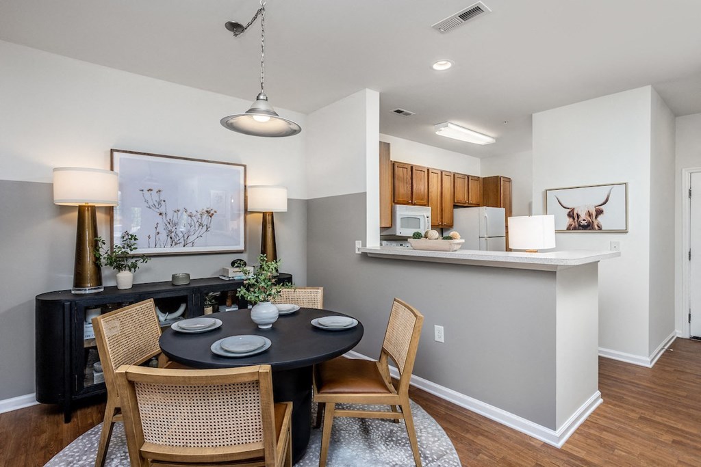 a dining area with a table and chairs and a kitchen in the background