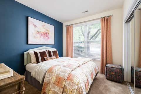 A bedroom with a bed, nightstand, and a painting on the wall.
