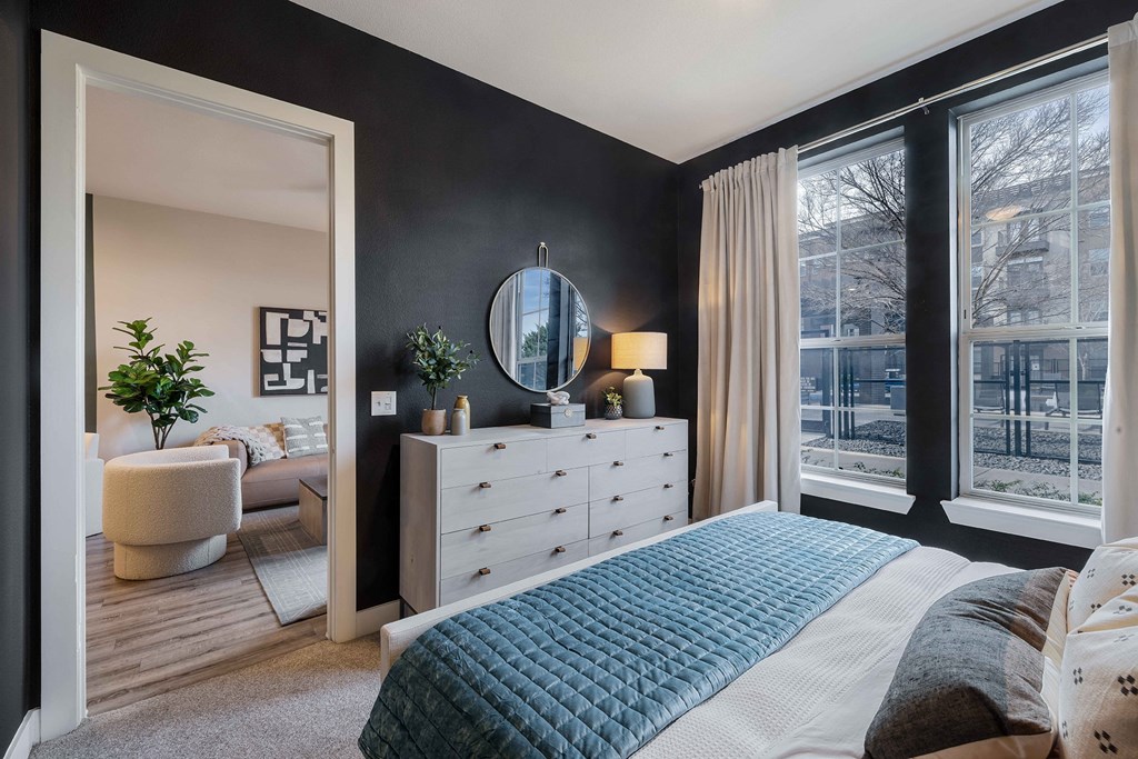 a bedroom with a bed and a dresser    and a large window