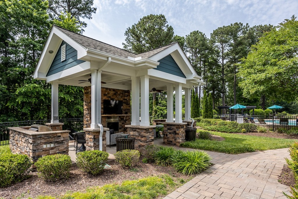 a pavilion with a stone fireplace and stone pillars