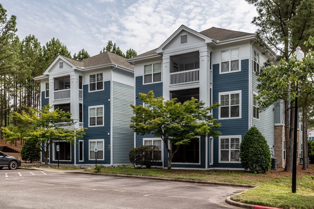 a row of blue and white apartment buildings with a parking lot