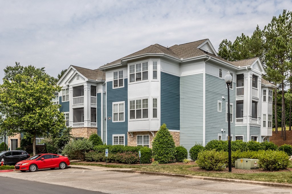 a blue and white apartment building with a red car parked in front of it